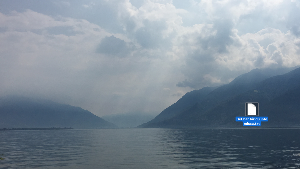 En skrivbordsbakgrund på en dator visande Lago Maggiore. På skrivbordet ligger bara en enda ikon.