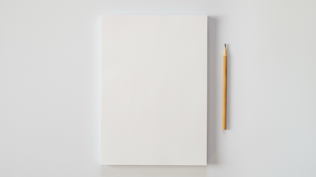Ett tomt vitt papper ligger prydligt på en ljus yta bredvid en vässad gul blyertspenna, vilket symboliserar en nystart eller outforskad potential.