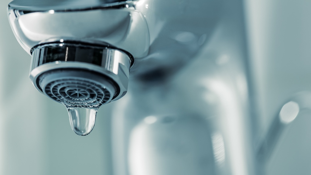 A close-up of a dripping tap with water droplets.