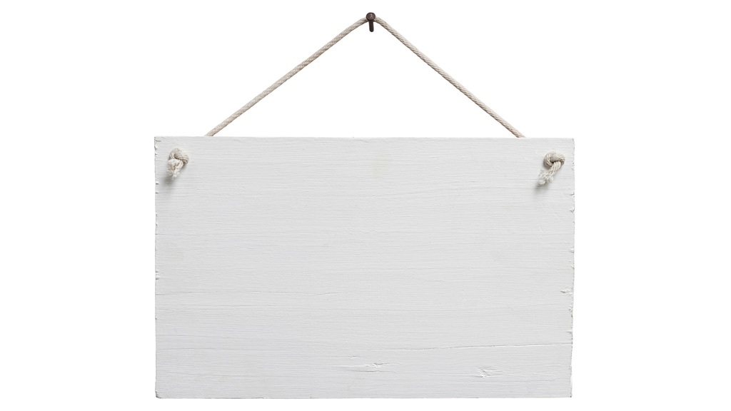 En vitlackerad träskylt som hänger i ett snöre på en spik. Det står ingenting på skylten.