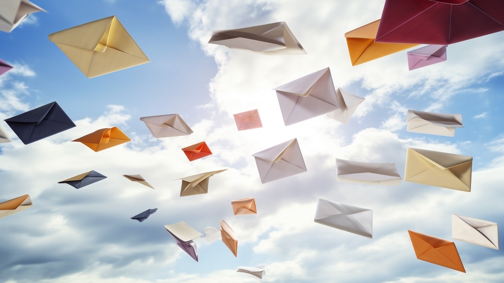 Colorful envelopes float through the air against a bright, cloudy sky, as if flying freely.