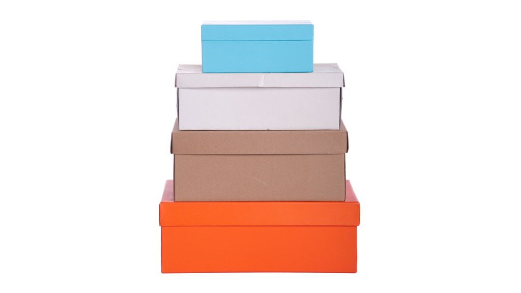 Fyra papplådor i olika storlekar staplade på varandra. En är orange, en brun, en vit och en blå.