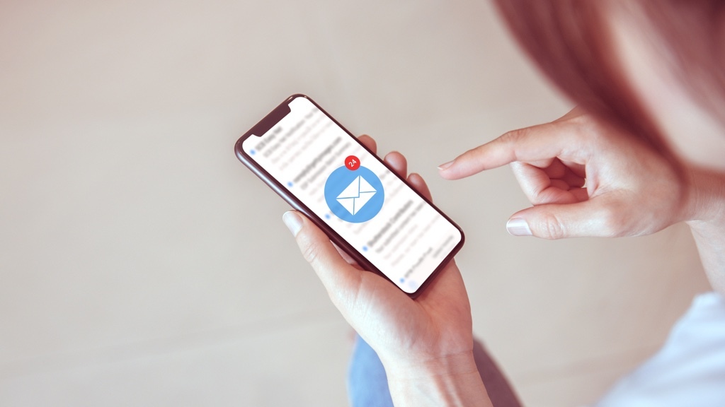 A person is holding a smartphone with an email app open, showing a large unread message icon with a notification badge indicating 24 new emails.
