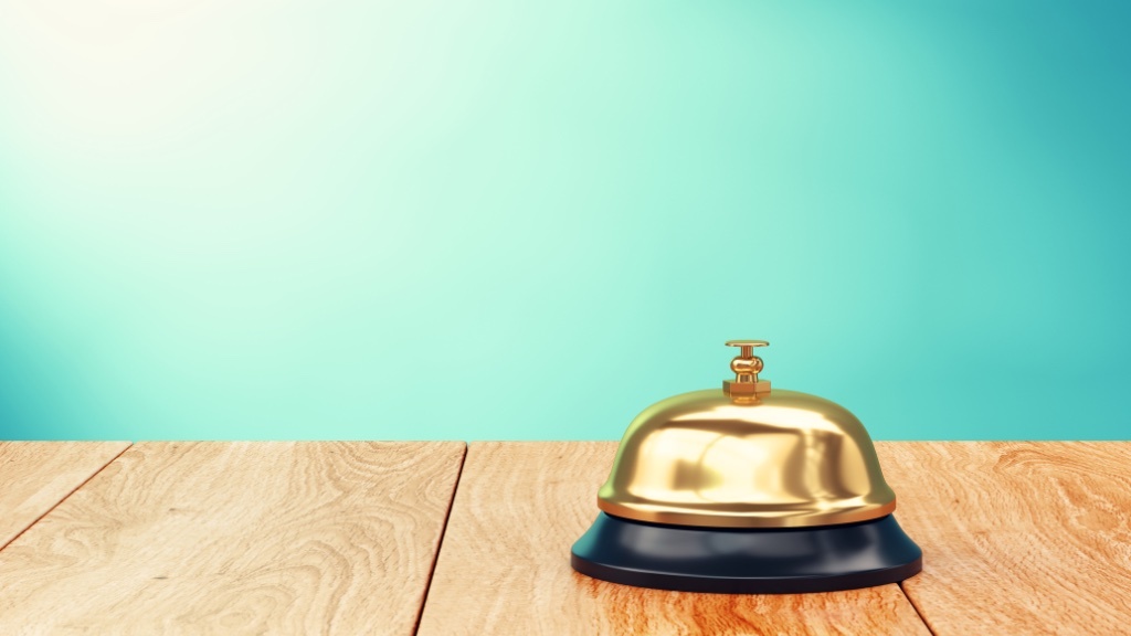 A service bell sits on a wooden surface against a teal background.