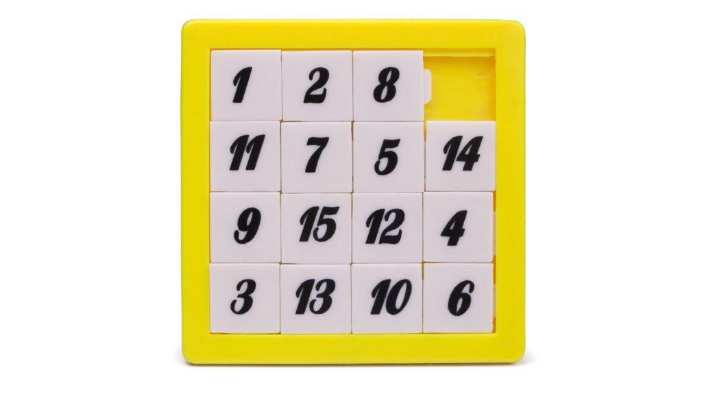 Ett gult femtonspel i plast med vita brickor med svarta siffror på
