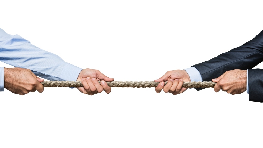 Two people in business attire are engaged in a tug-of-war, each pulling a rope in opposite directions.