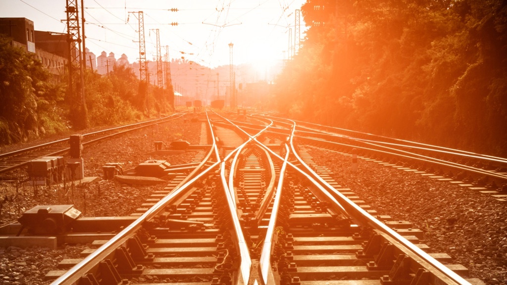 Two crossing railway tracks in the evening sunlight.