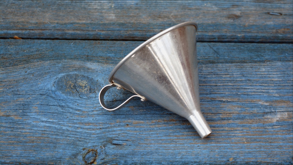 A metal funnel lies on a weathered blue wooden surface.