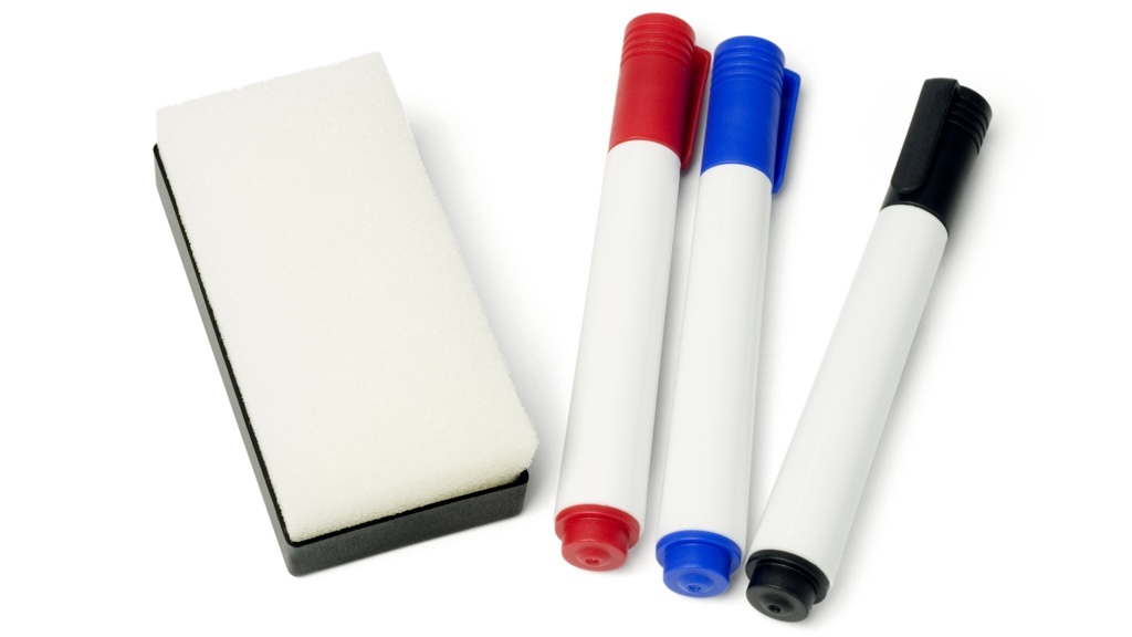 Tre whiteboardpennor (en röd, en blå, en svart) och en suddsvamp, alla på en vit yta.