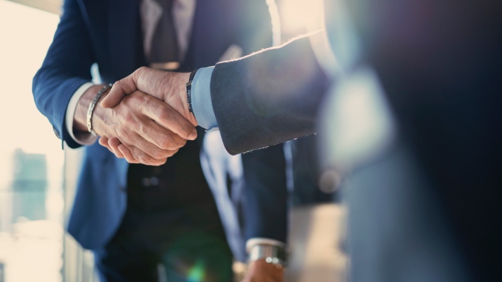 Two people in business attire are shaking hands, symbolizing an agreement or deal.