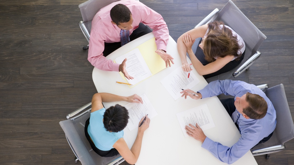 Four people in a meeting shot from above.