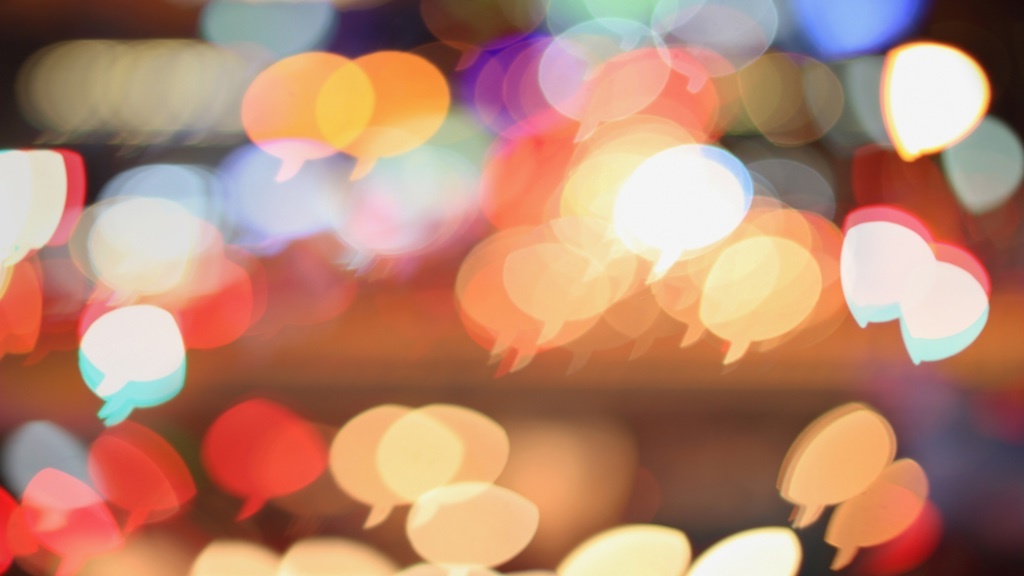 Colorful speech bubble-shaped bokeh lights are scattered across a blurred background.
