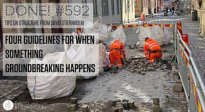 Workers are repairing a cobblestone street with barriers and large white bags of materials around them.