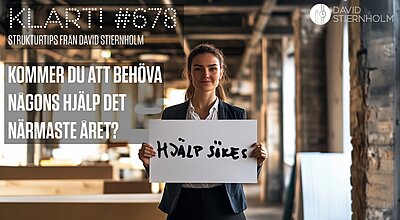 En kvinna i affärskläder står i ett öppet kontorsutrymme och håller en vit skylt med texten "Hjälp sökes" framför sig.