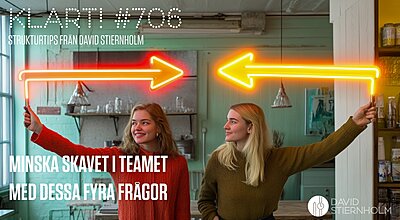 Två kvinnor ler mot varandra medan de håller i neonskyltar med pilar som pekar åt motsatta håll.