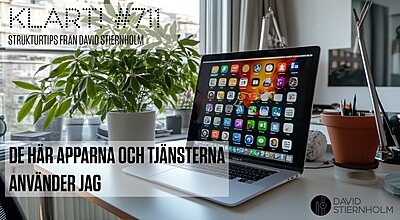 En bärbar dator med en färgglad skärm full av appikoner står på ett ljust skrivbord bredvid en grön växt och kontorsmaterial.