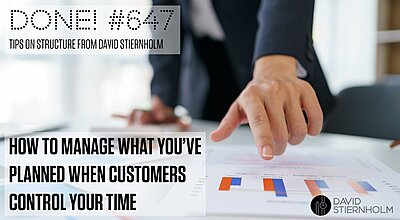 A person in business attire is pointing at a bar chart on a document laid out on a desk, with other papers and graphs scattered around, suggesting analysis or discussion of data.