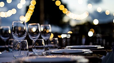 A beautifully set dinner table is ready under glowing string lights in the evening.