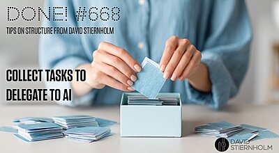 A person is placing small blue cards into a box while sorting several stacks on a table.