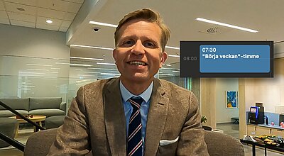 En leende man i brun kavaj och randig slips sitter i ett modernt kontorsutrymme, med ett kalendermeddelande synligt som visar "07:30 – 08:00 'Börja veckan'-timme."