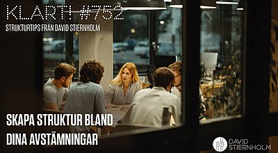Fem personer sitter samlade runt ett bord i ett modernt kontor och håller ett möte under industriella taklampor.