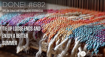 A colorful woven textile with fringed edges rests on a wooden surface, displaying intricate patterns in shades of blue, orange, red, purple, and cream.