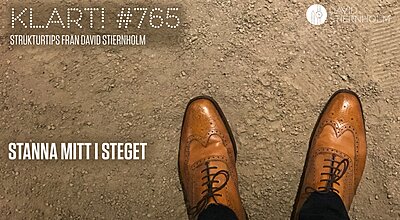 En person som bär ljusbruna läder-brogues av Oxford-modell står på en grusig mark.