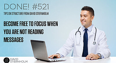 Physician at a white desk checking his email on a laptop smiling