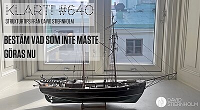 En skeppsmodell i trä står i en vitmålad fönstersmyg med utsikt över takåsarna i centrala Göteborg.