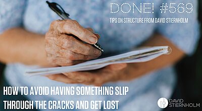 An elderly woman is writing with a black ballpoint pen on a white notepad. She wears a light blue sweater.