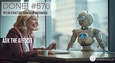 A blonde middle-aged business woman is laughing with a humanoid robot at a desk.