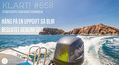 En motorbåt skapar kölvatten på det klara blå havet, med en klippig kustlinje i bakgrunden.